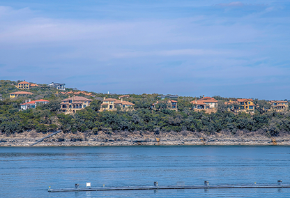 Mansions on a slope with Lake Austin waterfront- Austin, Texas. Rich neighborhood near the lake with mansions and villas on a sloped land against the sky.