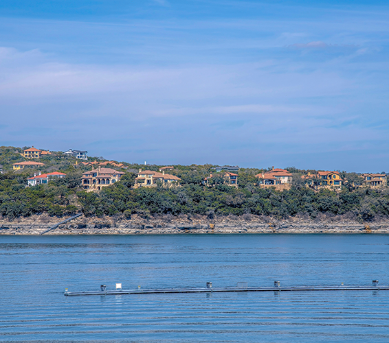 Mansions on a slope with Lake Austin waterfront- Austin, Texas. Rich neighborhood near the lake with mansions and villas on a sloped land against the sky.